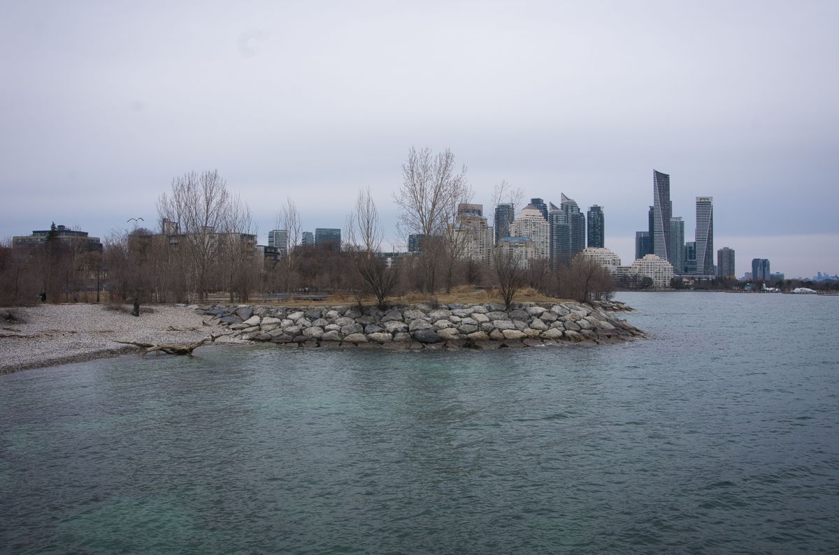 The rocky shoreline of Mimico Waterfront Park on Lake Ontario, with condo towers along the shore behind it.